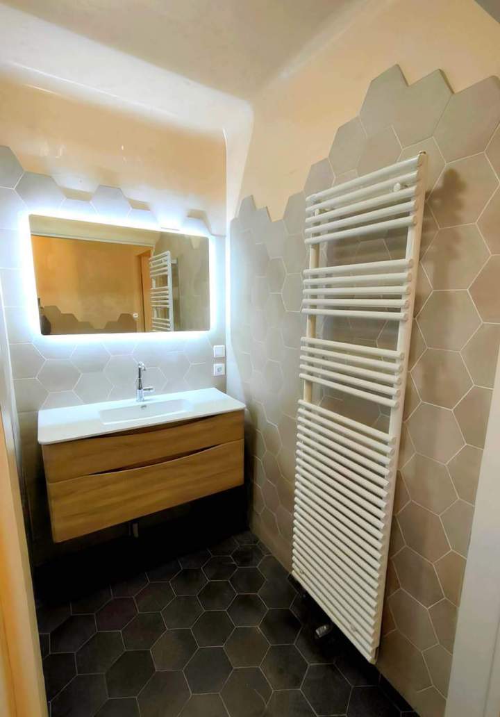 Vanité en bois flottante, miroir rétroéclairé et sèche-serviettes mural blanc, installés dans une petite salle de bains, Yvelines